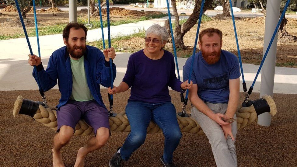 Peace activist Vivian Silver, centre, sits on a swing next to her two sons, including Yonatan Zeigan on the left